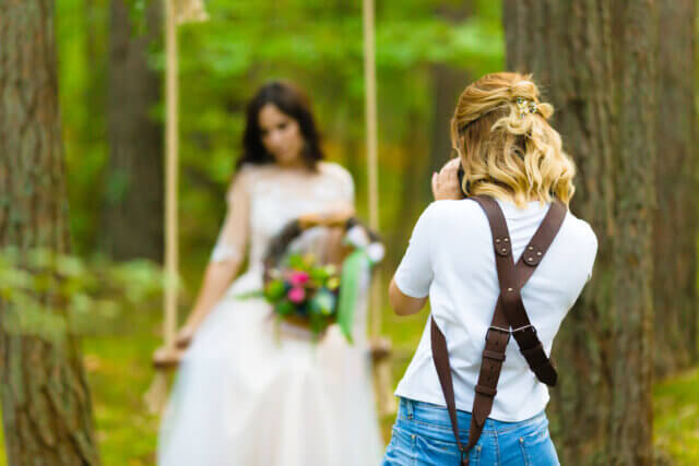 A photographer photographs a bride on a swing