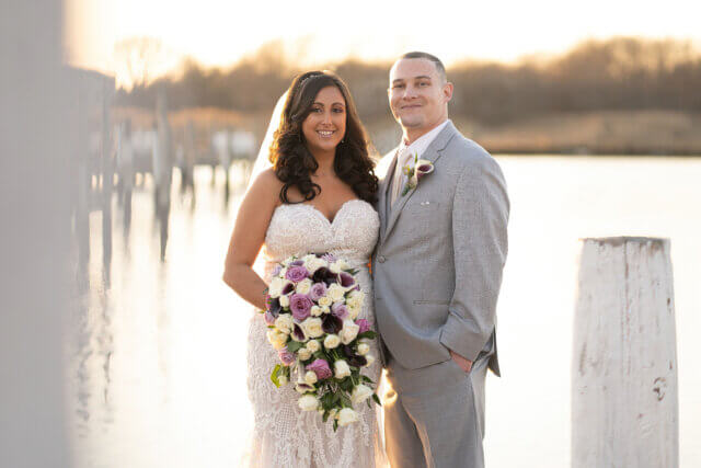 A bride and groom smile by the waterfront - Life Art Photographers