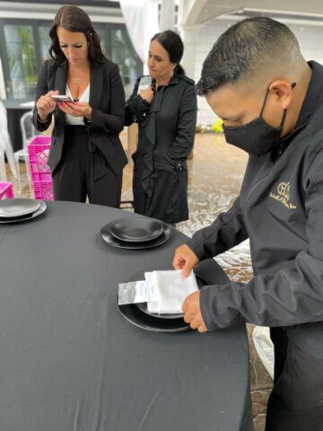 A wedding planner on her cell phone as staff sets the table