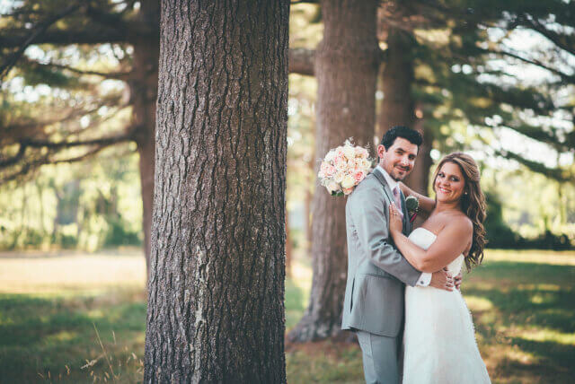 Bride and groom posing by a tree