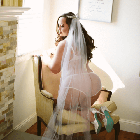 A bridal boudoir model on a chair in her veil