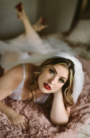 A bridal boudoir model in a veil on a bed