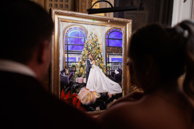 A couple looking at a picture painted By Brittany Branson