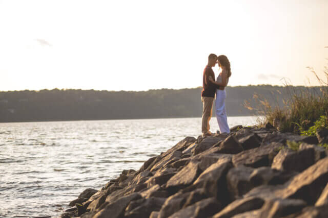 a man and woman standing on rocks by water