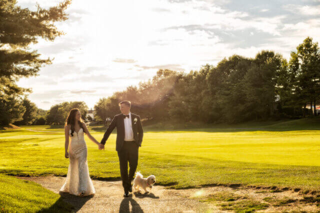 a man and woman holding hands and walking a dog