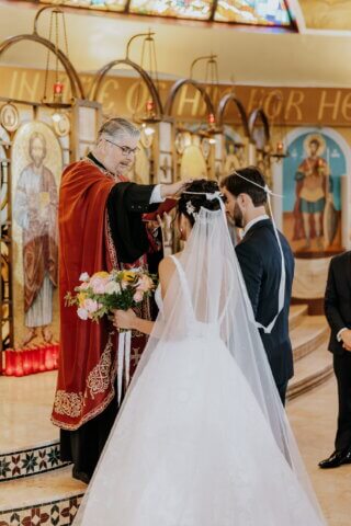 bride and groom at a Greek wedding with the priest