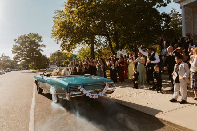 Bride and groom in a vintage car that says just married