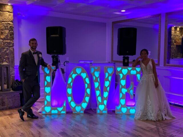 A couple in front of a DJ booth with the letters LOVE