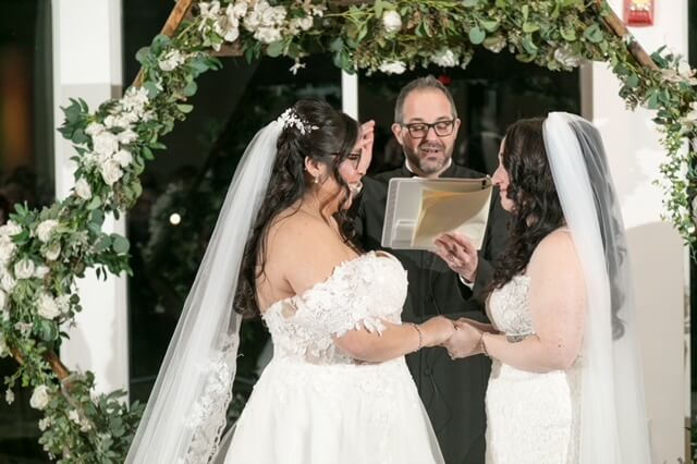 Two brides saying their vows with an officiant