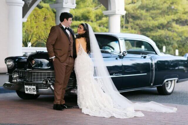 A bride and groom in front of a 1954 Cadillac