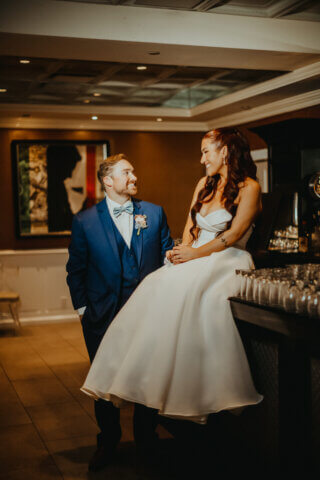 Bride siitting a bar looking at her groom