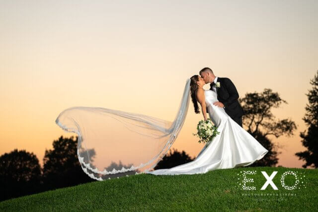A bride and groom kissing with her veil blowing